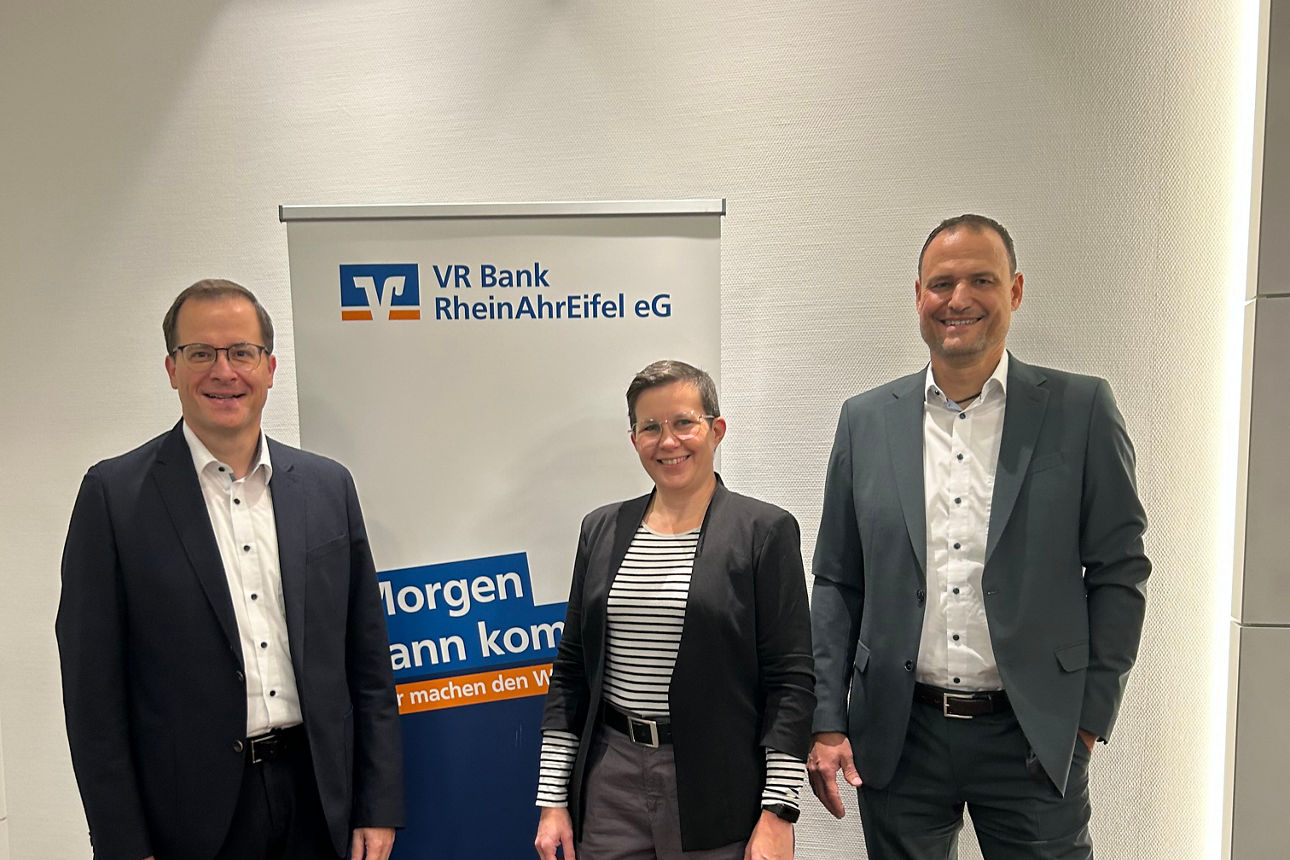 Drei Personen vor einem VR Bank RheinAhrEifel eG Banner mit den Slogans „Morgen kann kommen“ und „Wir machen den Weg frei“.