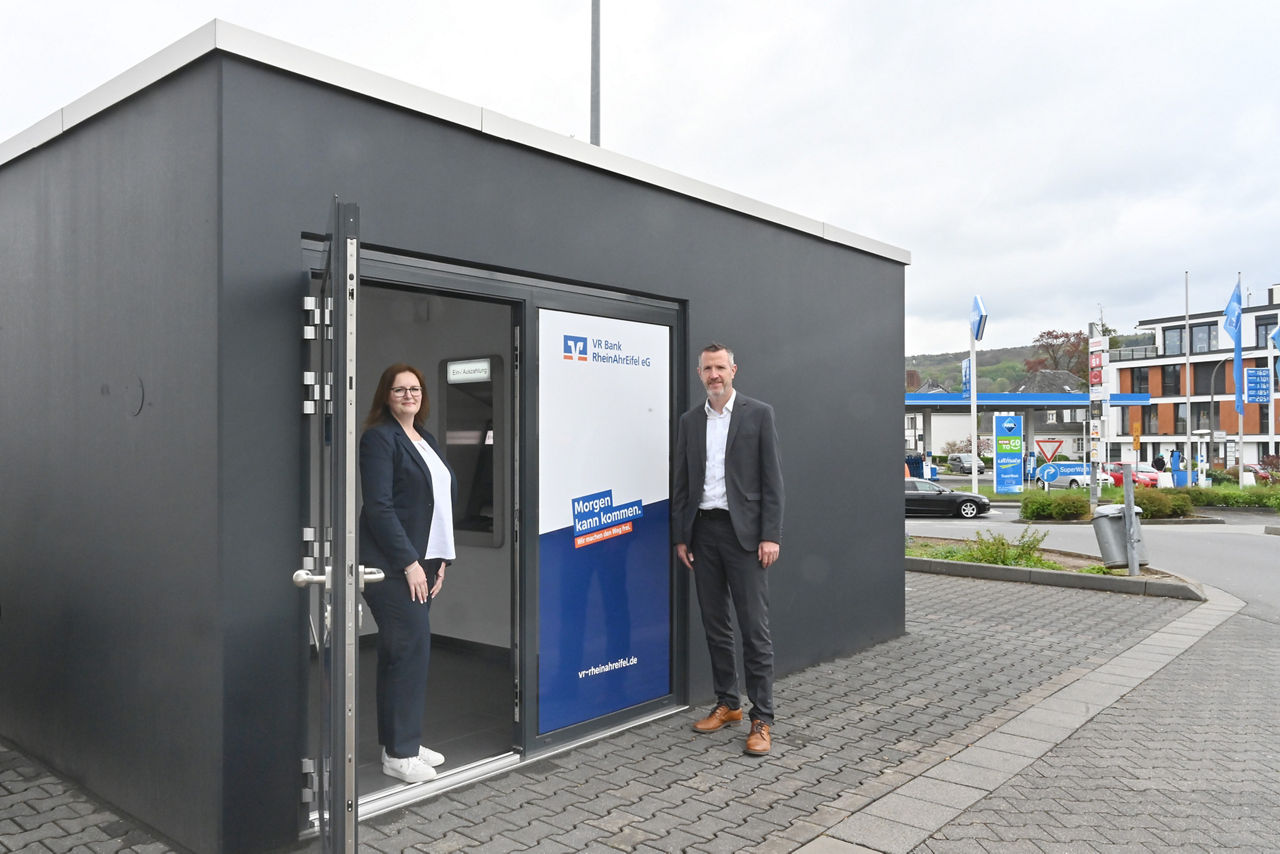 Zwei Personen stehen vor einer SB-Filiale einer Bank.
