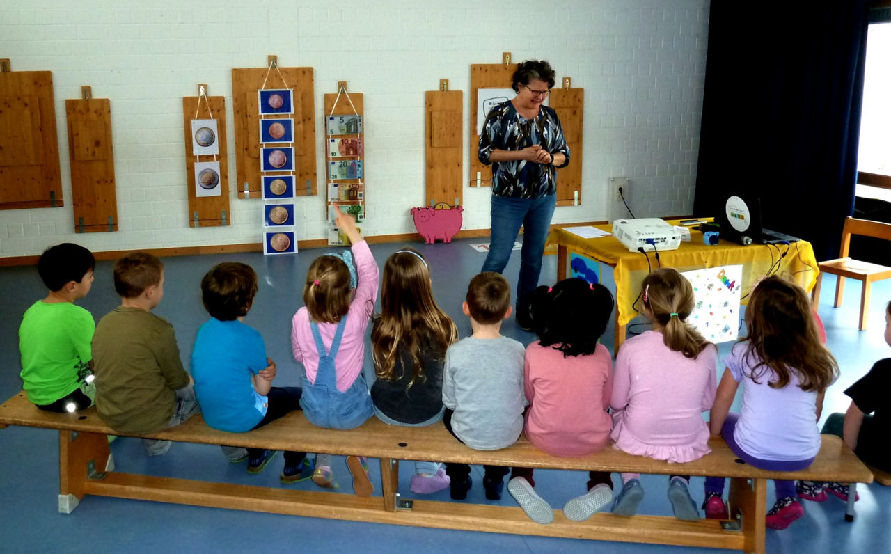 Kinder sitzen auf einer Bank im Kindergartenund hören einem Vortrag zu