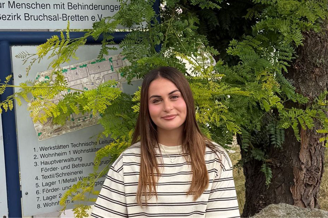 Eine junge Frau repräsentiert das Projekt Seitenwechsel und steht vor dem Firmenschild der Lebenshilfe.