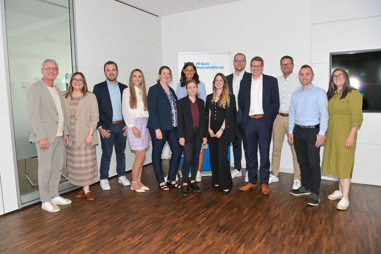 Elf Mitarbeitende der VR Bank RheinAhrEifel eG stehen in einem Büroraum zum Gruppenfoto.