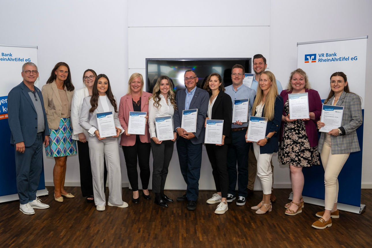 Gruppenfoto mit 13 Menschen bei VR Bank RheinAhrEifel eG, zehn halten Zertifikate, Slogan: "Morgen kann kommen".