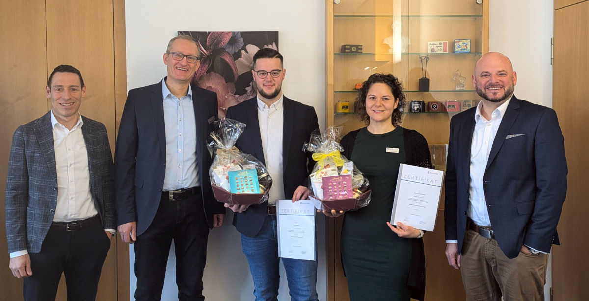 Mitarbeiter mit Geschenkkorb stehen mit Führungskräften nebeneinander