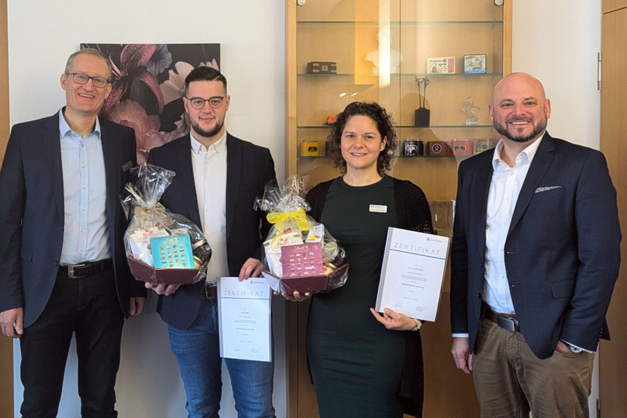 Mitarbeiter mit Geschenkkorb stehen mit Führungskräften nebeneinander