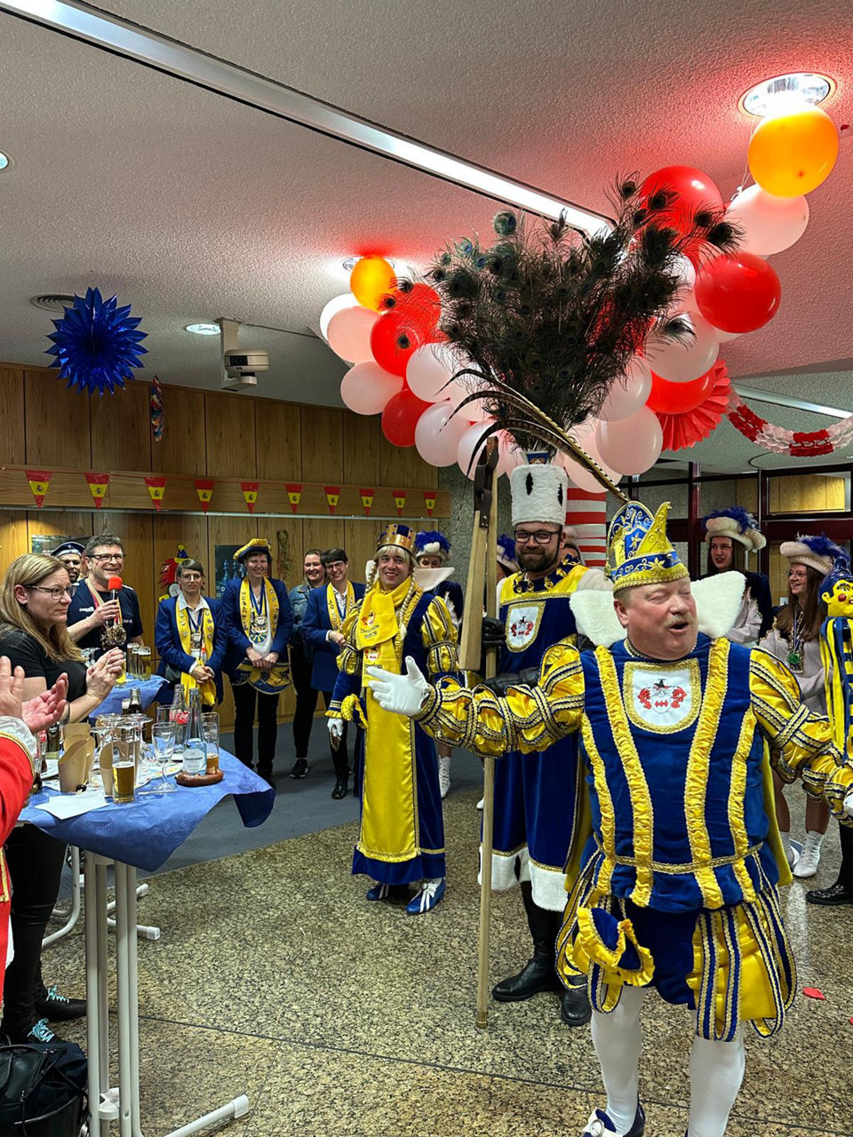 Mehrere Personen in karnevalistischer Kleidung singen und tanzen zusammen.