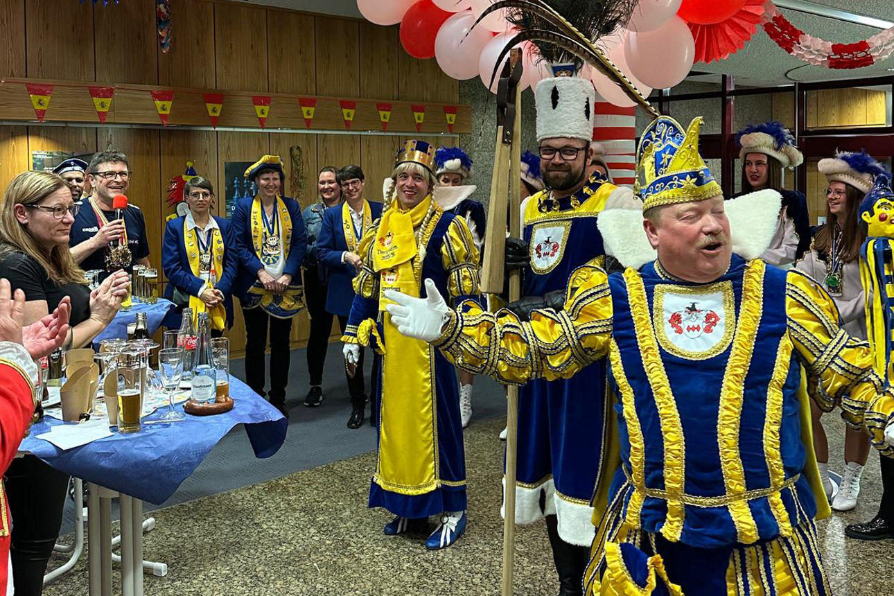 Mehrere Personen in karnevalistischer Kleidung singen und tanzen zusammen.