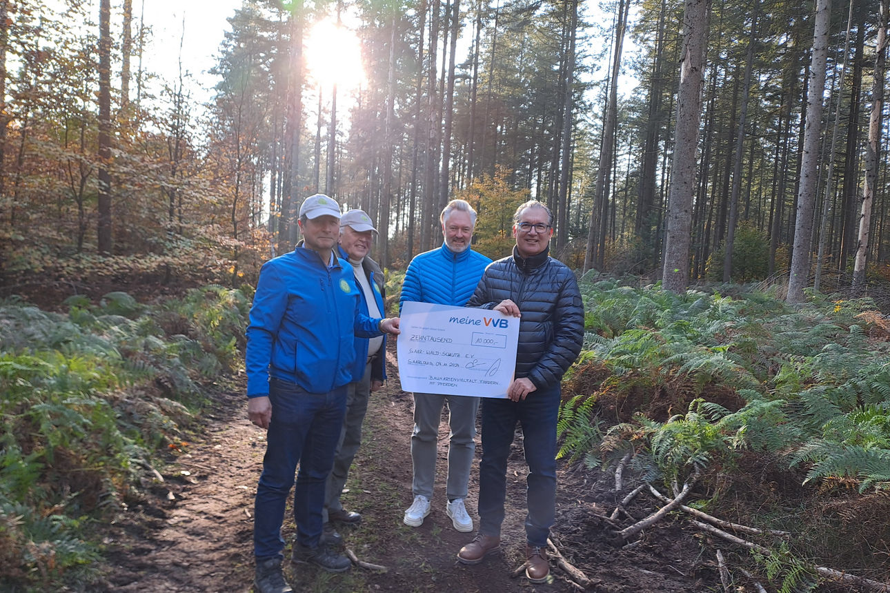 Männer im Wald bei der Spendenscheckübergabe