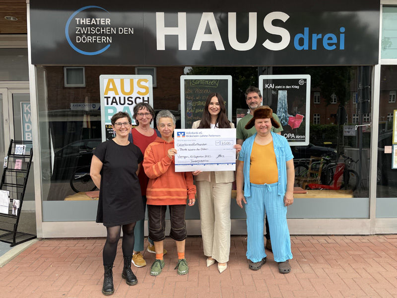Symbolische Scheckübergabe vor dem Theater zwischen den Dörfern