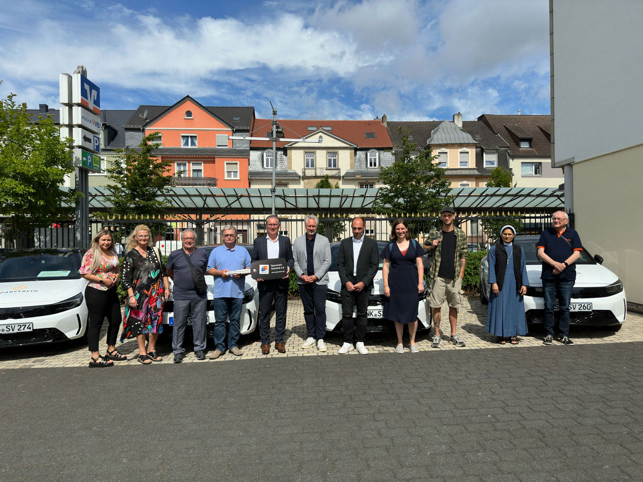 Menschen bei der Schlüsselübergabe der Spendenfahrzeuge