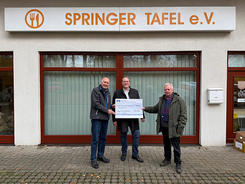 Drei Männer stehen vor dem Gebäude des Springer Tafel e. V. und halten einen Überreichungsscheck in den Händen.