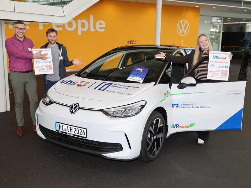 Zwei Personen stehen links und eine Person steht rechts neben dem eVRmobil