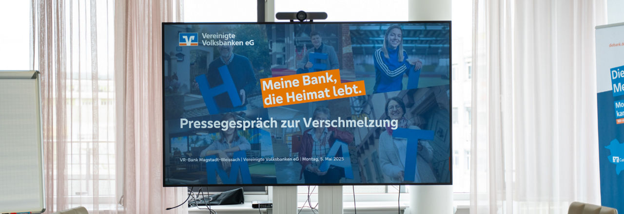 Großes Bildschirm mit Standbild Pressegespräch zur Verschmelzung