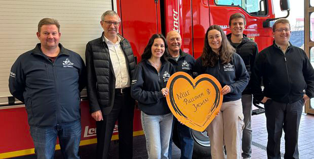 Eine Gruppe von Menschen posiert gemeinsam vor einem Feuerwehrauto
