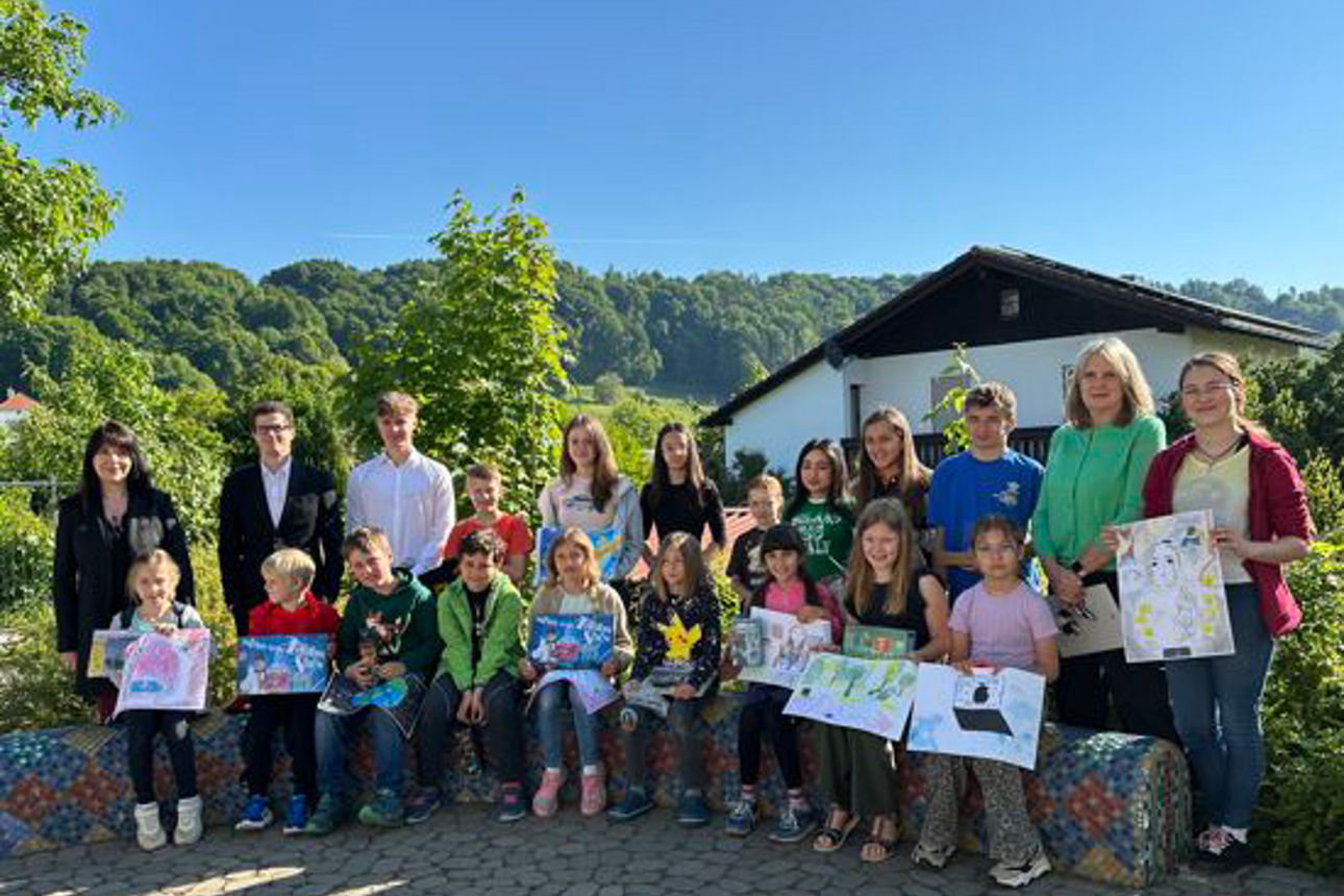 Eine Gruppe von Kindern zeigt gemalte Bilder in die Kamera