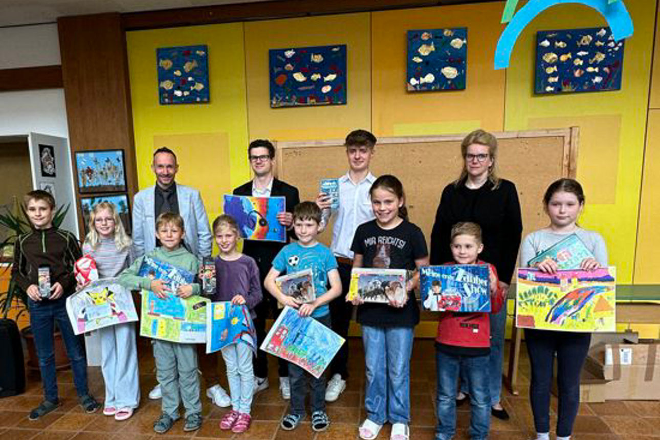 Eine Gruppe von Kindern zeigt gemalte Bilder in die Kamera