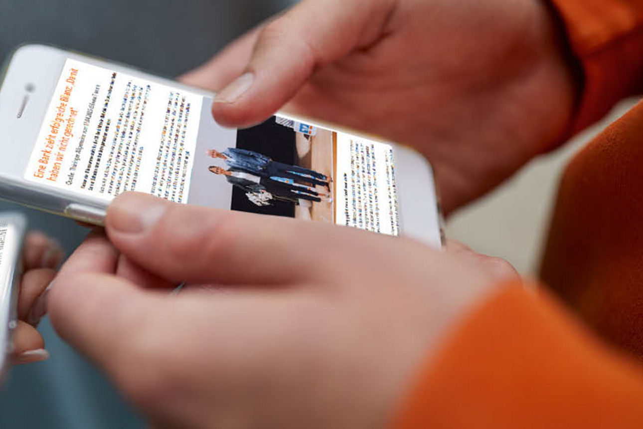 Hände, die zwei Handys halten auf denen Pressemitteilungen zu sehen sind