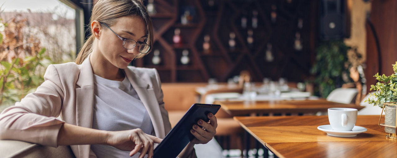 Junge Frau im Kafee beim Lesen am Tablet