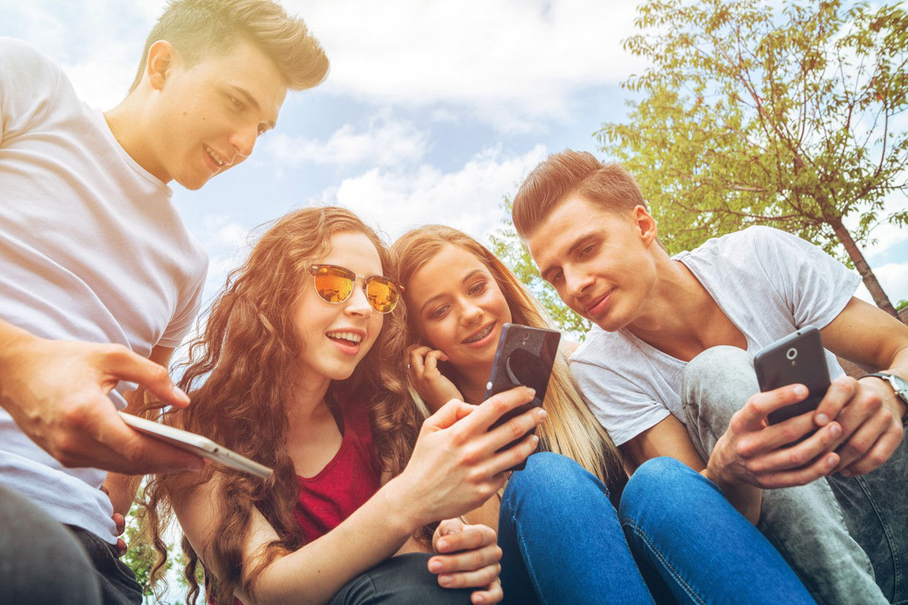 Eine Gruppe Jugendlicher schauen auf ihre Smartphones