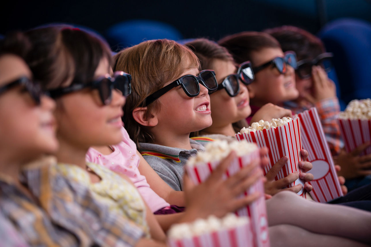 Kinder im Kino mit 3D Brille und Popcorn