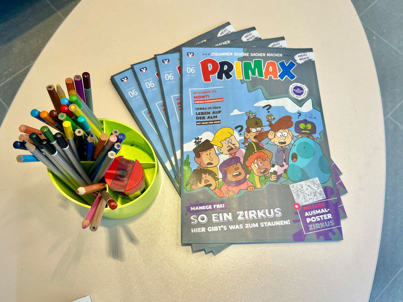 Primax-Hefte liegen auf neben Buntstiften auf dem Tisch