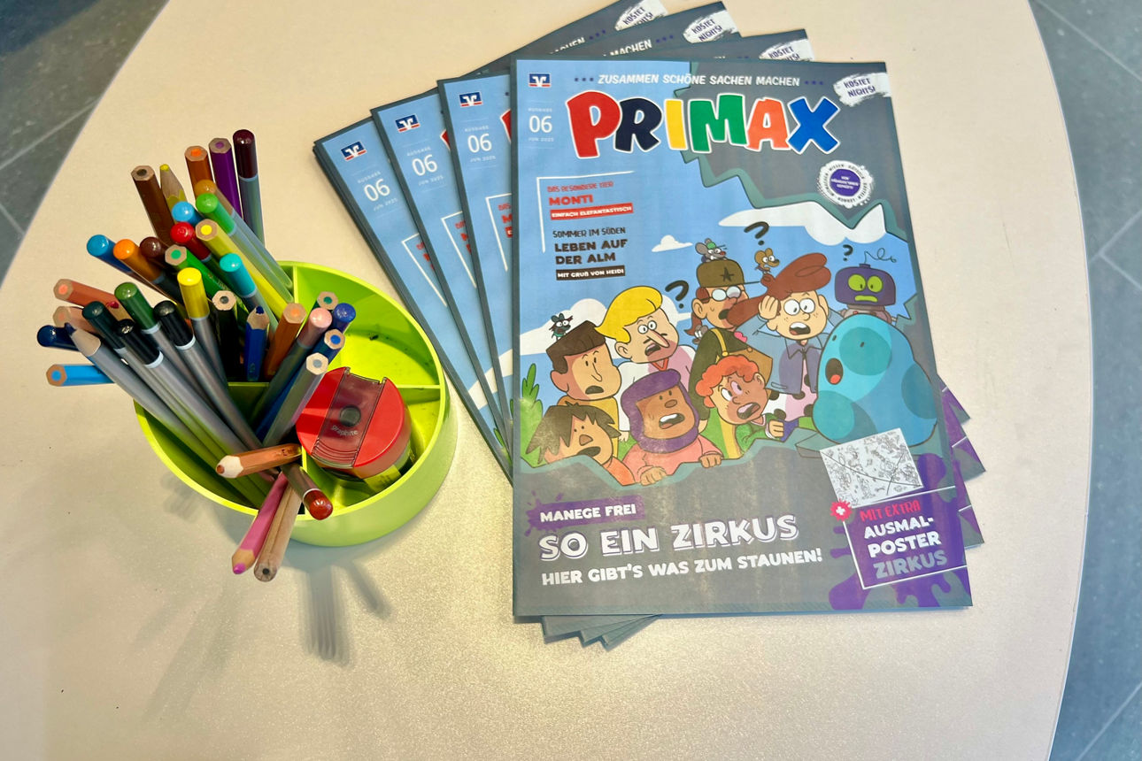 Primax-Hefte liegen auf neben Buntstiften auf dem Tisch