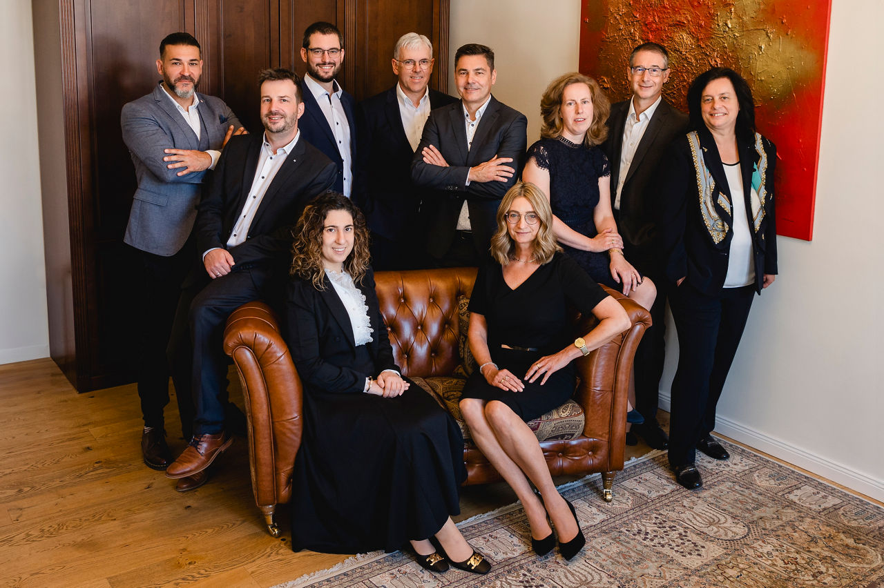 Zehn Mitarbeitende der PrivatBank befinden sich in einem Büro. Zwei von ihnen sitzen auf einer Couch