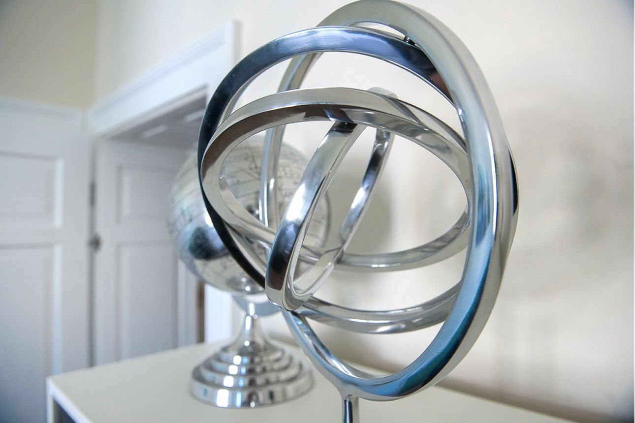 Eine Metall-Skulptur und ein Globus aus Metall stehen auf einem Schrank