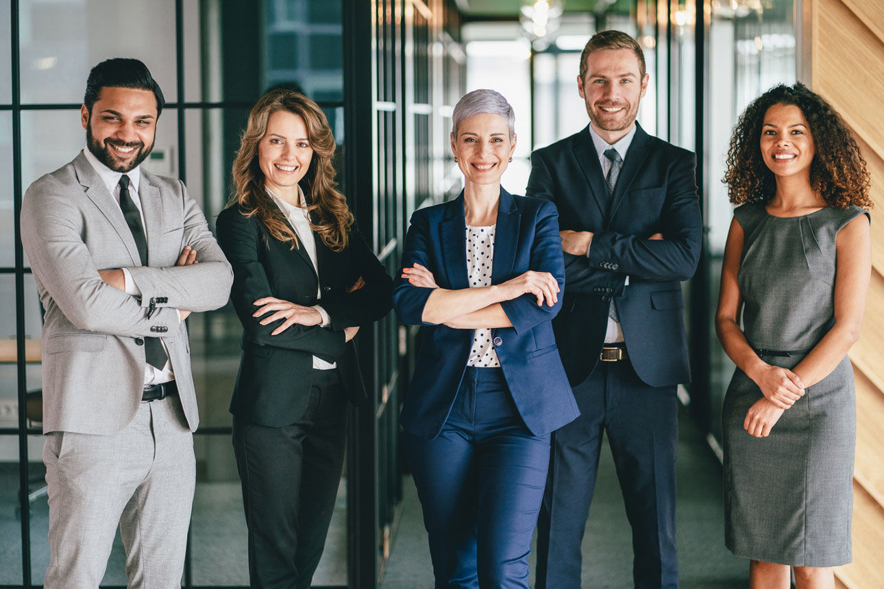 Zwei Männer und drei Frauen stehen lächelnd nebeneinander