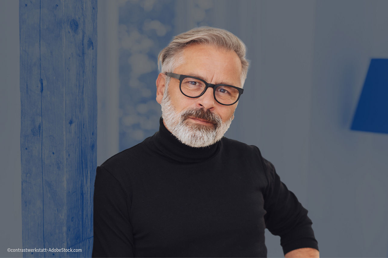 Mann mit Brille in schaut auf das Modell einer Immobilie