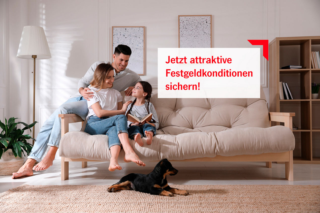 Eine junge Familie sitzt im Wohnzimmer auf dem Sofa und liest.