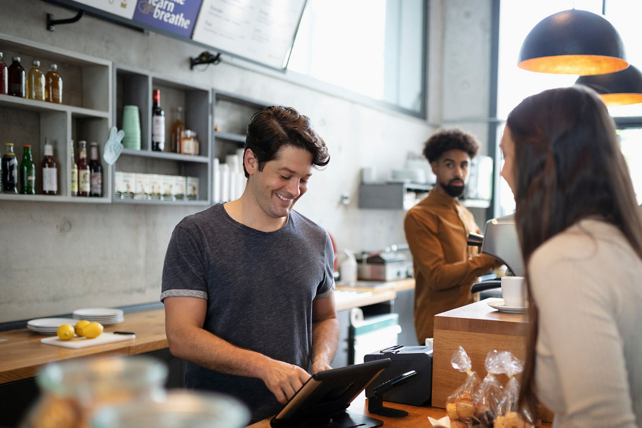 Frau steht im Cafe an der Kasse