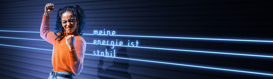 Eine Frau steht vor einem leuchtenden Neon-Schild und lächelt