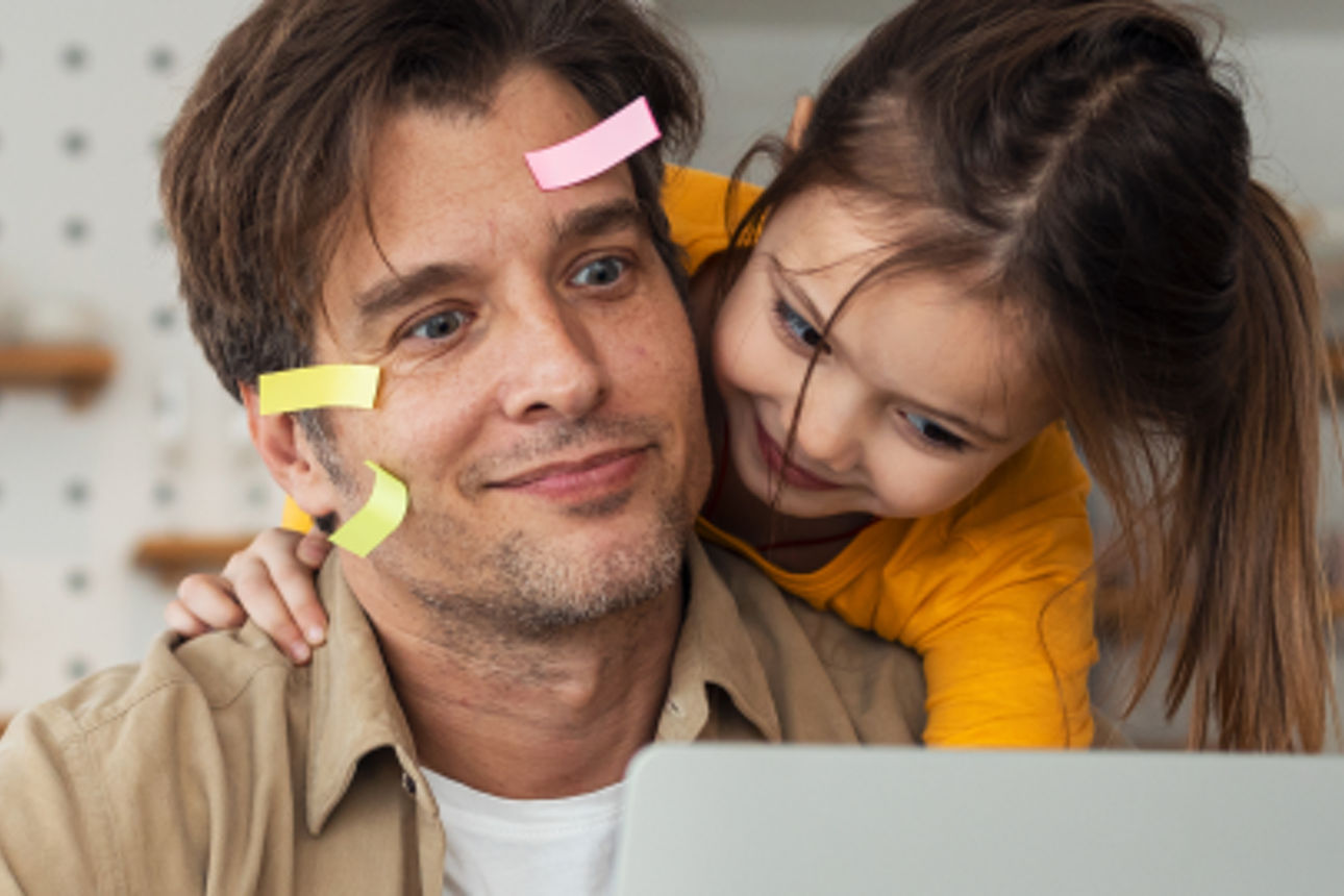 Mann Post-it im Gesicht und Kind schauen in einen Laptop