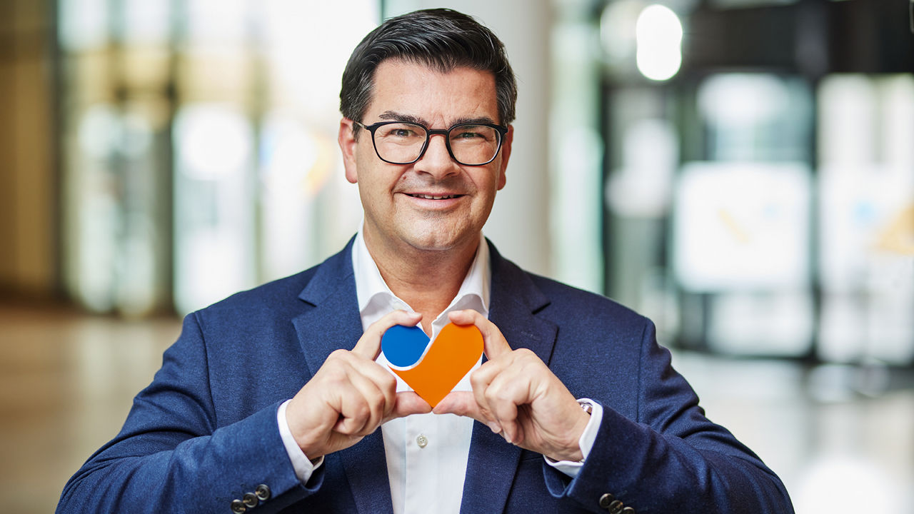 Vorstandsmitglied Jürgen Neutgens mit einem orange blauen Herz in den Händen