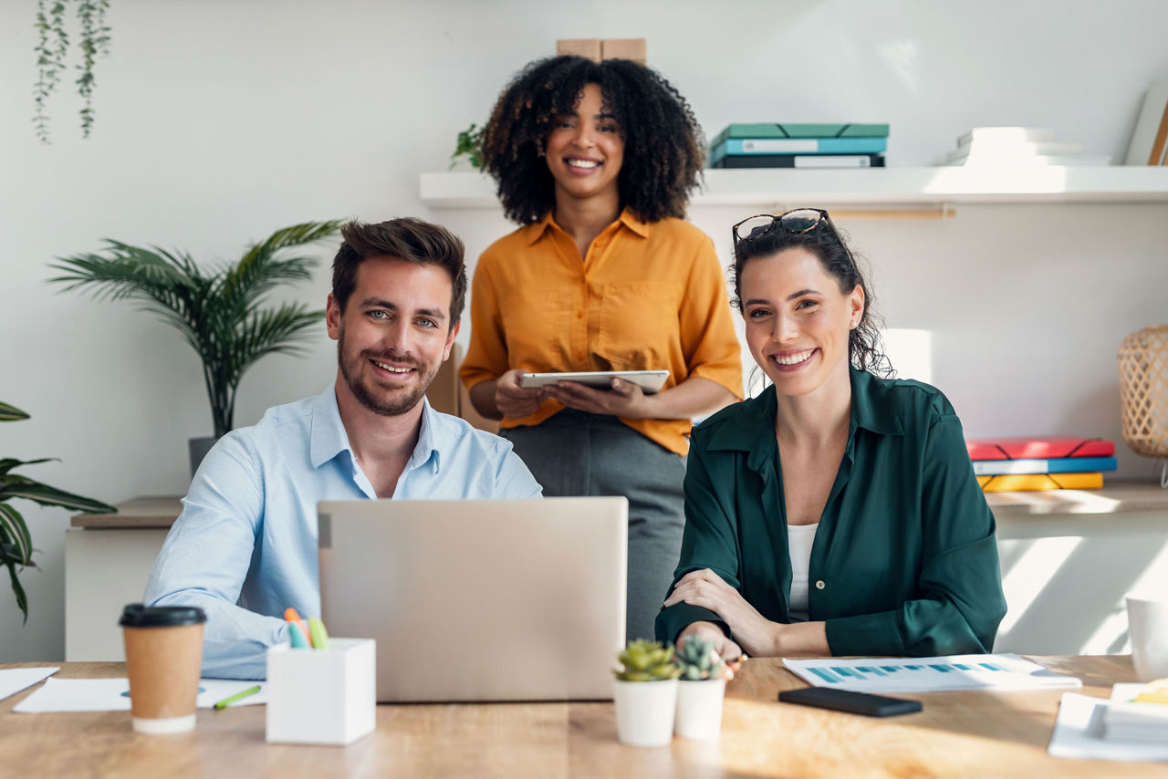 Drei Menschen lachend zusammen am Arbeiten