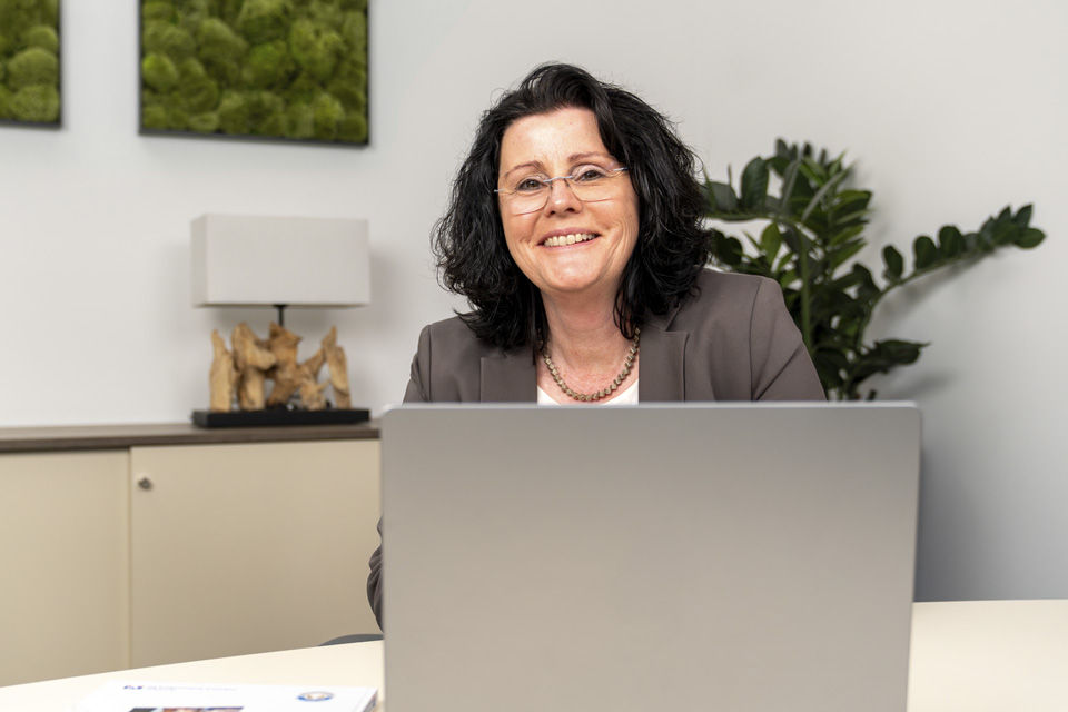 Frau sitzt am Arbeitsplatz an ihrem Laptop