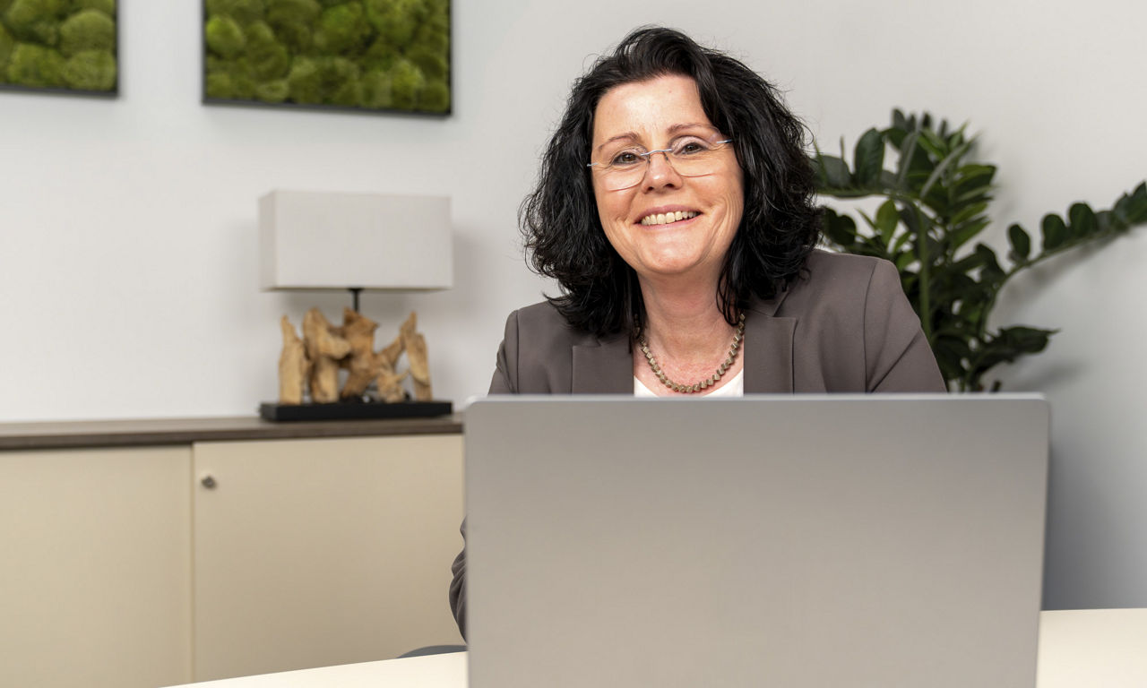 Frau sitzt am Arbeitsplatz an ihrem Laptop