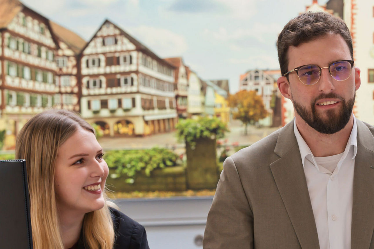 Junge Frau und Mann lächelnd an ihrem Arbeitsplatz