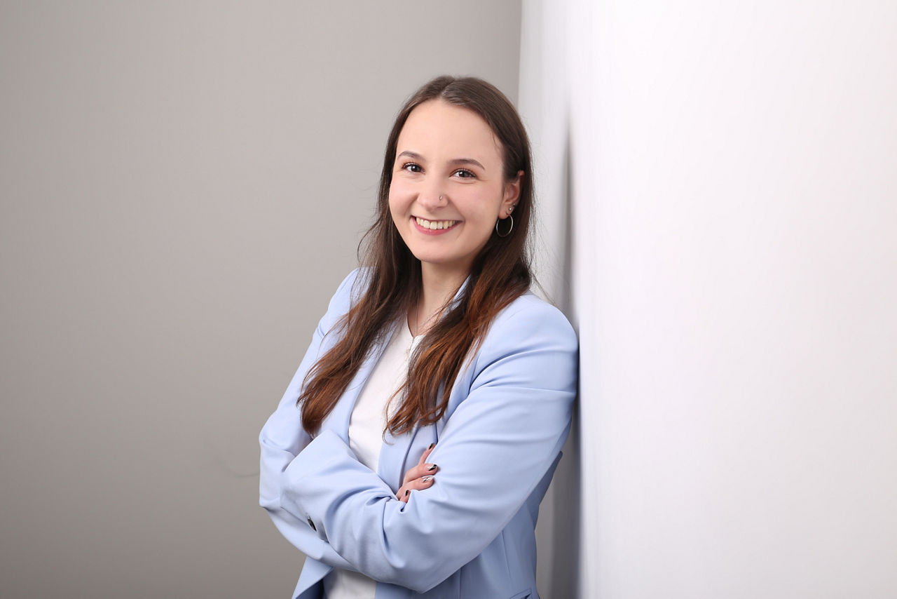 Mitarbeiterin der Bank, Zsófia Borbély, lehnt an Wand und lächelt in die Kamera