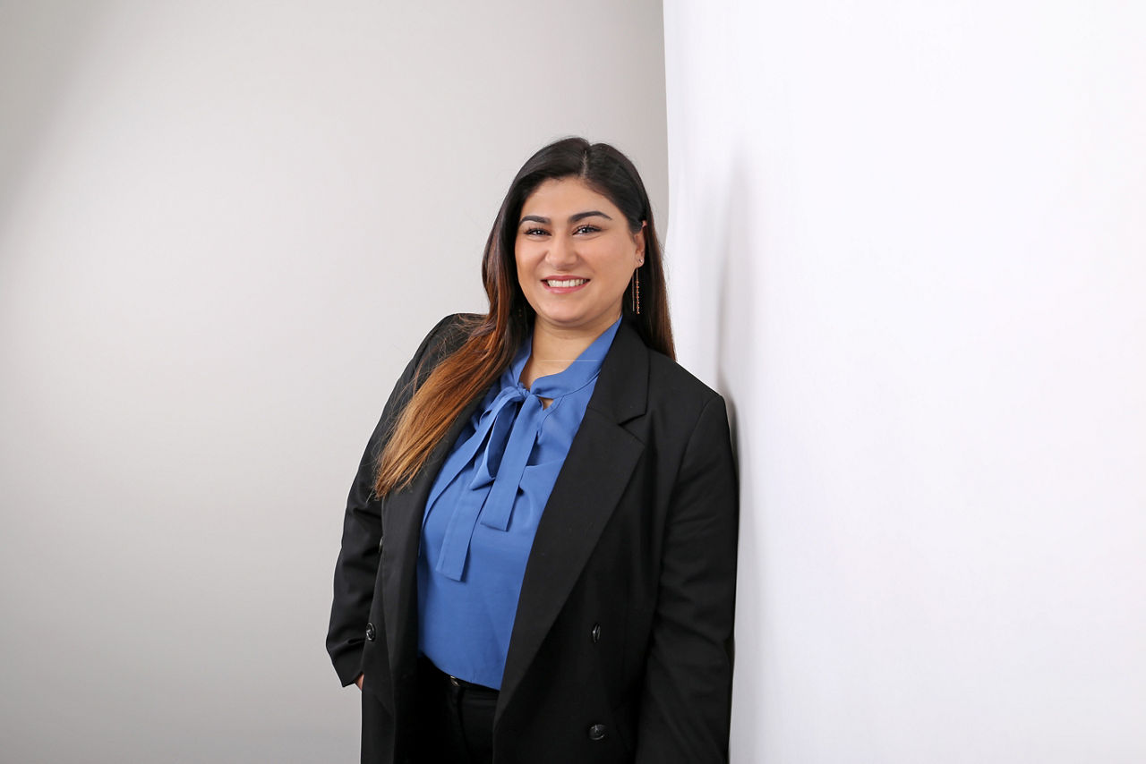 Mitarbeiterin der Bank, Özlem Güleryüz, lehnt an Wand und lächelt in die Kamera