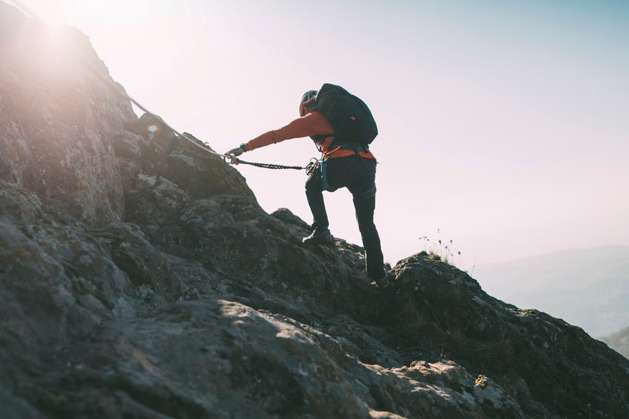 Ein Bergsteiger zieht sich an einem Seil den Berg hoch