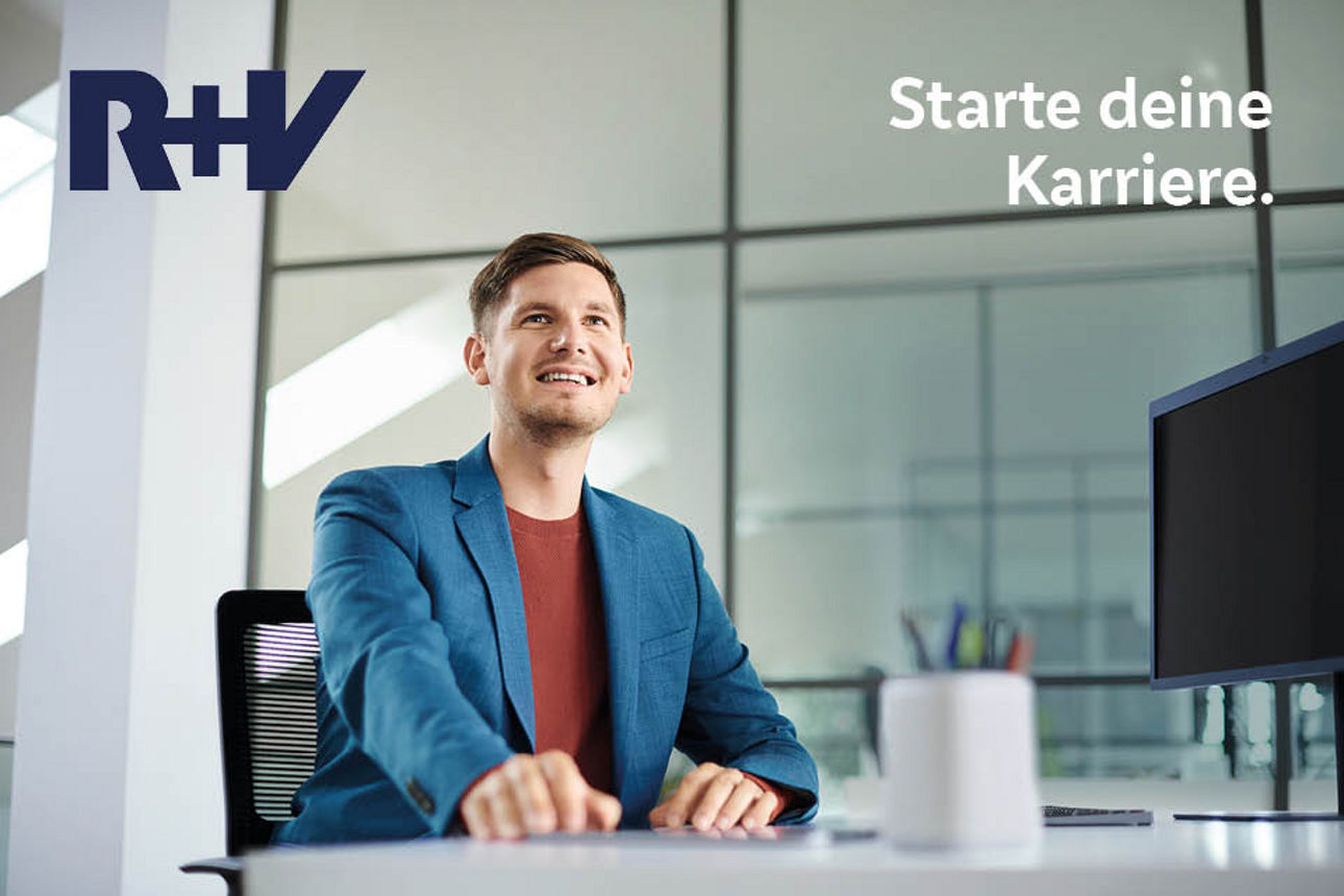 Mann sitzt lächelnd am Schreibtisch