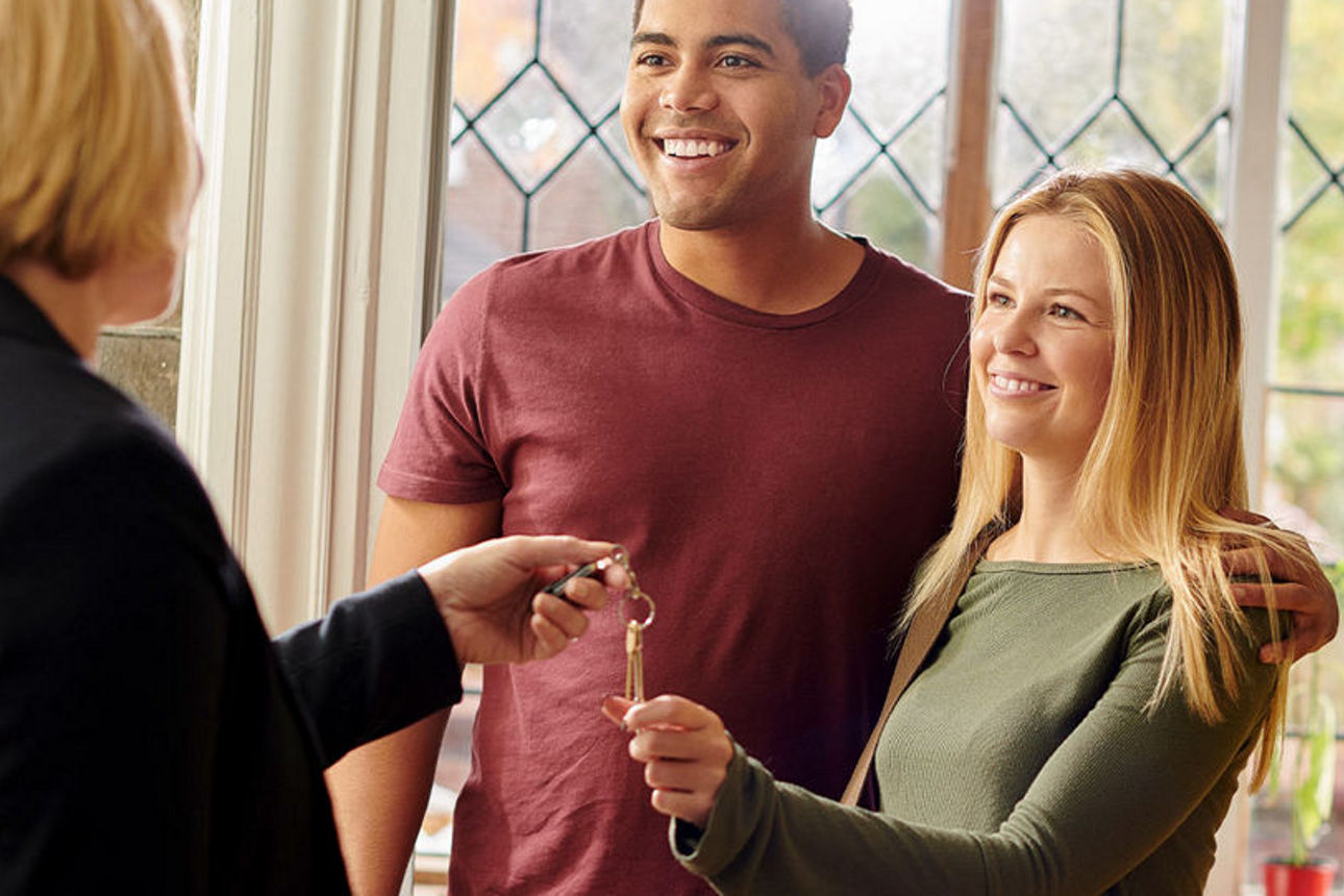 Frau und Mann bekommen von eienr Frau Ihren Wohnungschlüssel übergeben