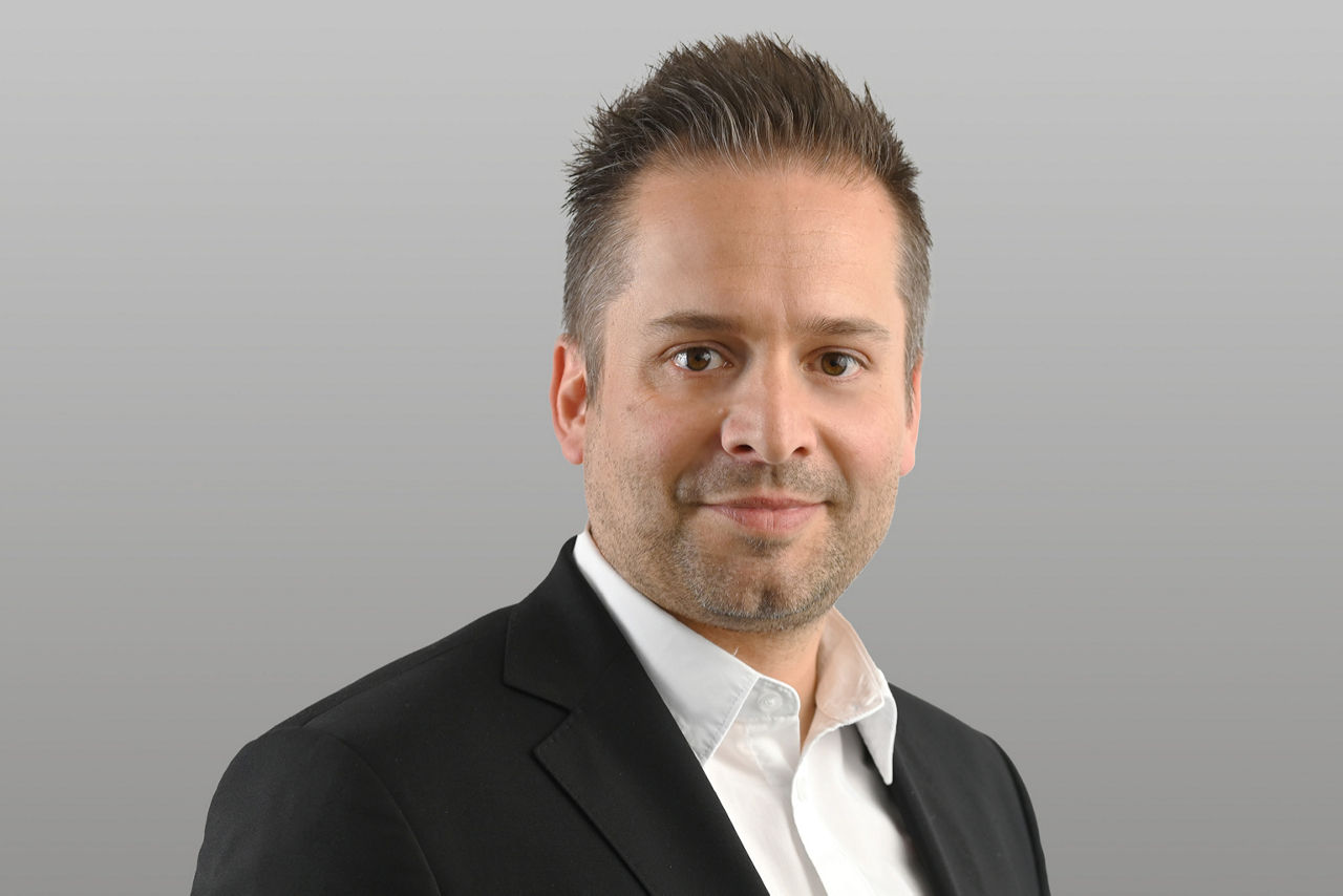 Privatkundenberater Bastian Römmler vor grauen Hintergrund