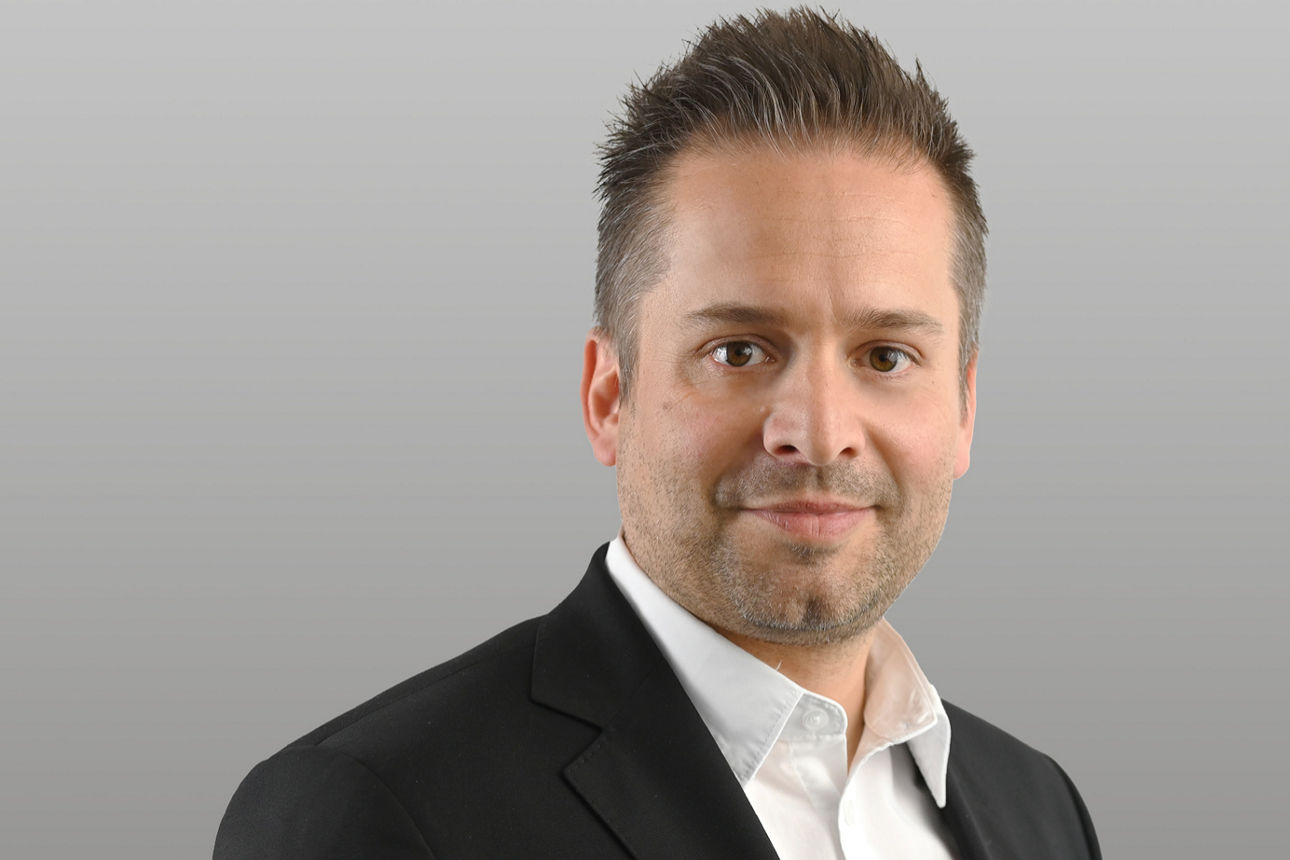 Privatkundenberater Bastian Römmler vor grauen Hintergrund
