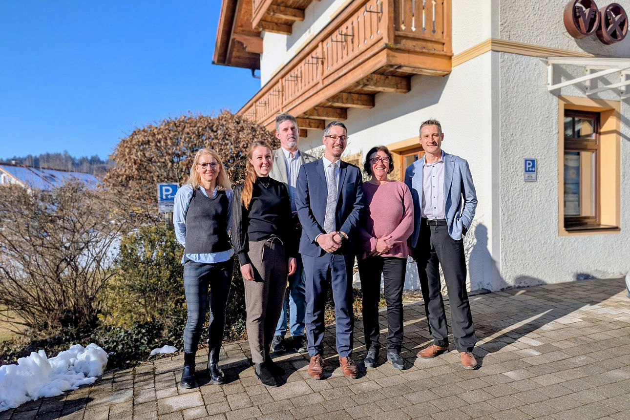 Sech Personen stehen in freien bei sonnigem Wetter und lächeln in die Kamera.