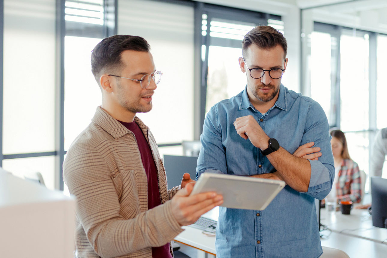 Zwei Männer im Beratungsgespräch, der Berater zeigt Inhalte auf dem Tabelett