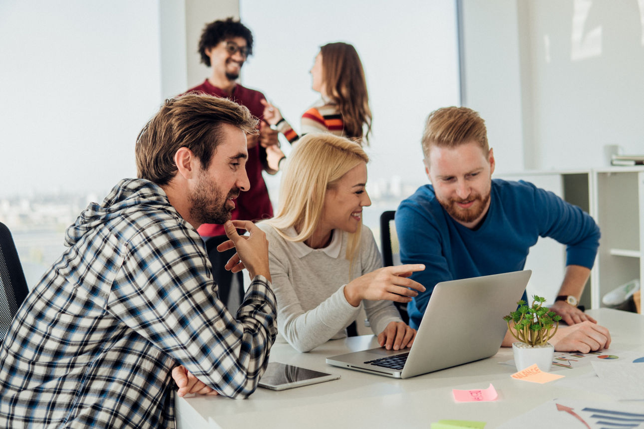 Personen sprechen und schauen auf einen Laptop