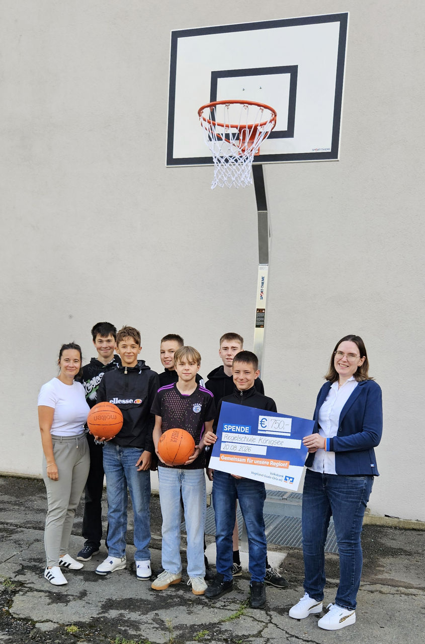 Übergabe der Präsentationsschecks unter dem Basketballkorb an die Schüler 