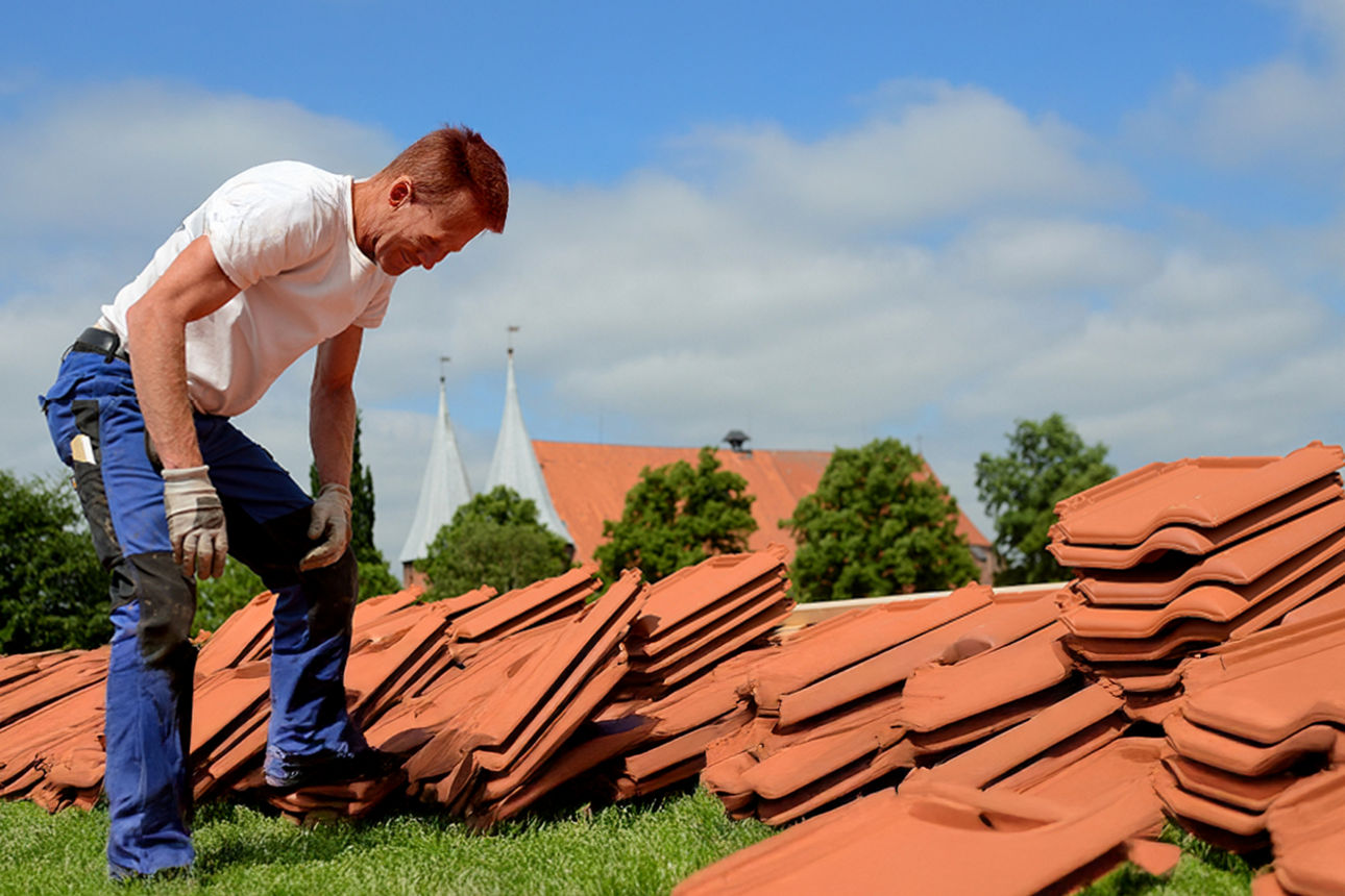 Ein Handwerker vor einem Stapel Dachpfannen